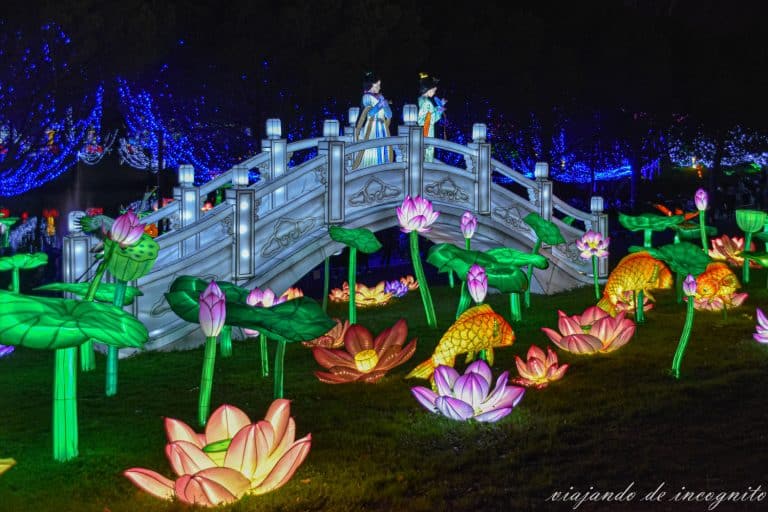 Farolillos chinos que representan un puente blanco con dos mujeres sobre él y rodeado de flores y peces de noche en el festival de las linternas ,Francia