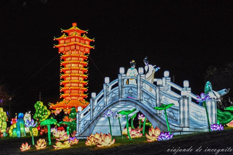 Farolillos chinos que representan un puente con dos personas y una torre roja de noche
