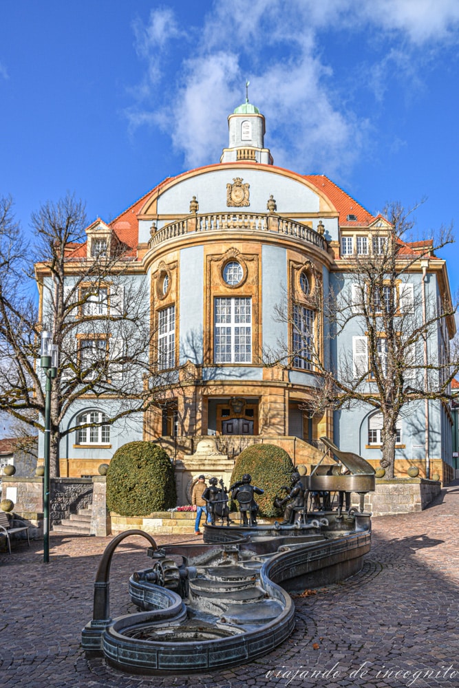 Edificio azul del antiguo ayuntamiento de Donaueschingen con una fuente con esculturas de músicos que se pueden mover.