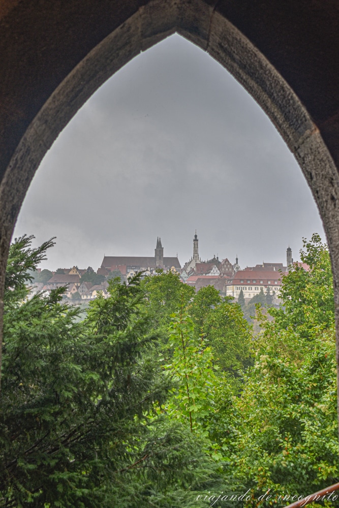 Vistas del centro de Rothenburg ob der Tauber rodeado de árboles a través de un arco de la torre Kalk