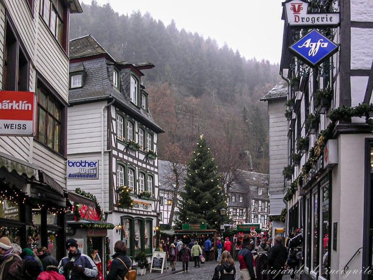 Calle con casas de entramado de madera y pizarra de Monschau decoradas en navidad y al fondo un árbol de navidad del mercado navideño