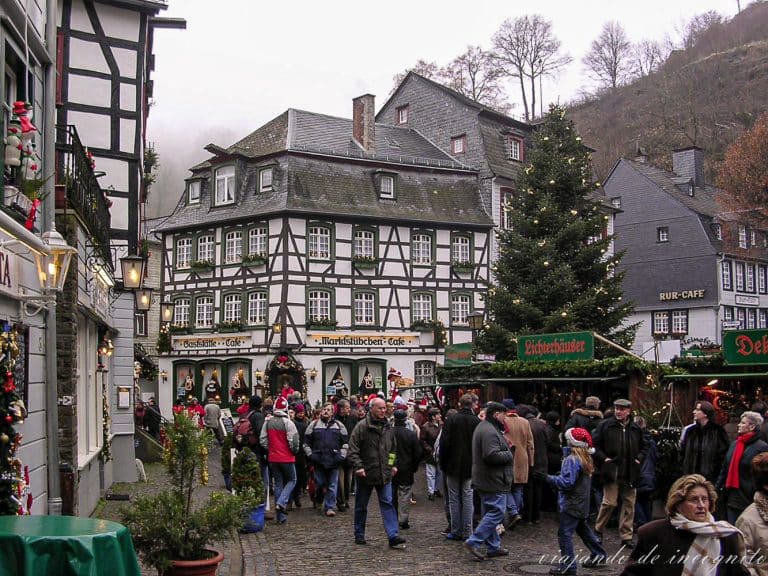 Gente disfrutando del mercado de navidad de Monschau entre casas de entramado de madera blancas y con el tejado de pizarra