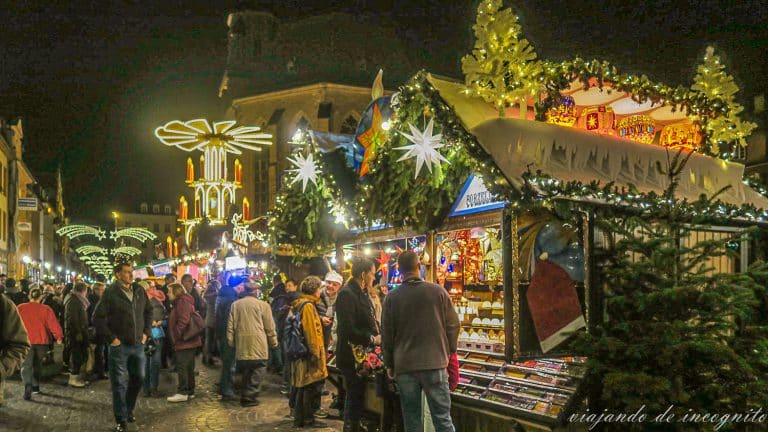 Gente mirando los Puestos de navidad del mercado de Heidelberg iluminados por la noche