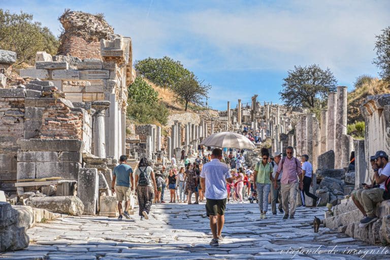 Numerosas personas recorriendo la avenida de los curetes, con el templo de Adriano en primer plano.
