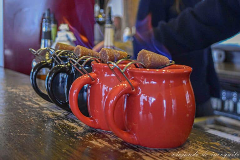 Cuatro tazas de Feuerzangenbowle, dos negras y dos rojas, con el azúcar empapado en alcohol y flambeado