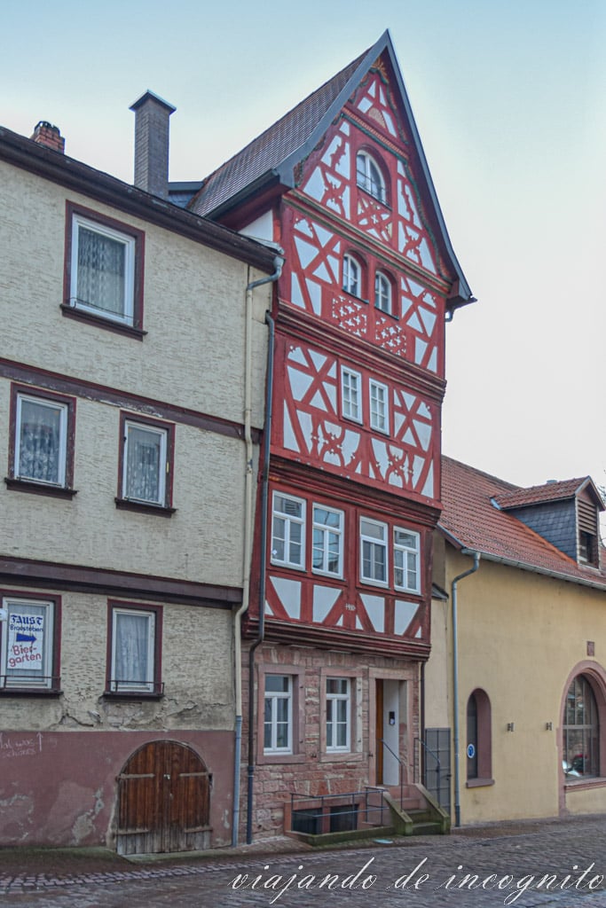 Casa estrecha de entramado de madera blanca y roja de cinco pisos e inclinada hacia delante