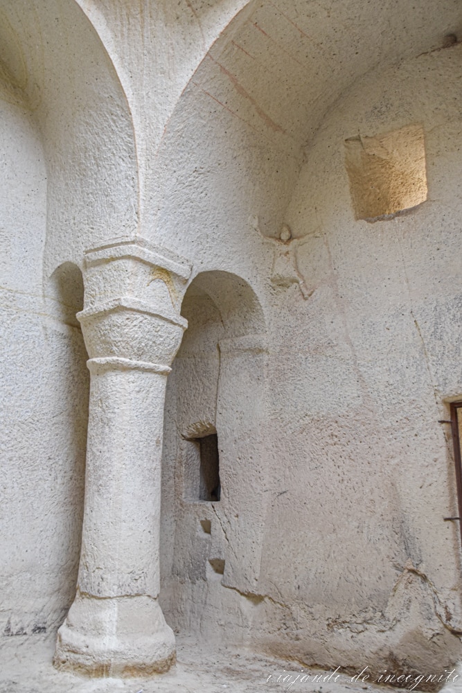 columna blanca del Monasterio Hallacdere junto a una pequeña representación en la pared de un hombre escalando