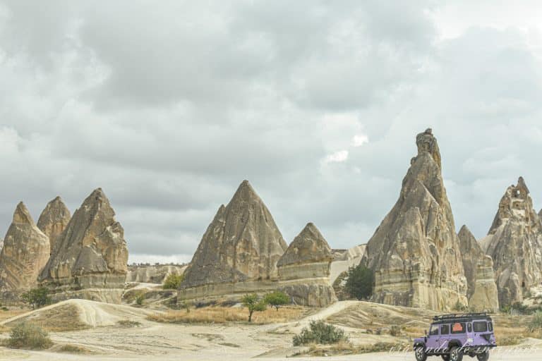 Furgoneta morada cruzando unas formaciones rocosas con forma piramidal