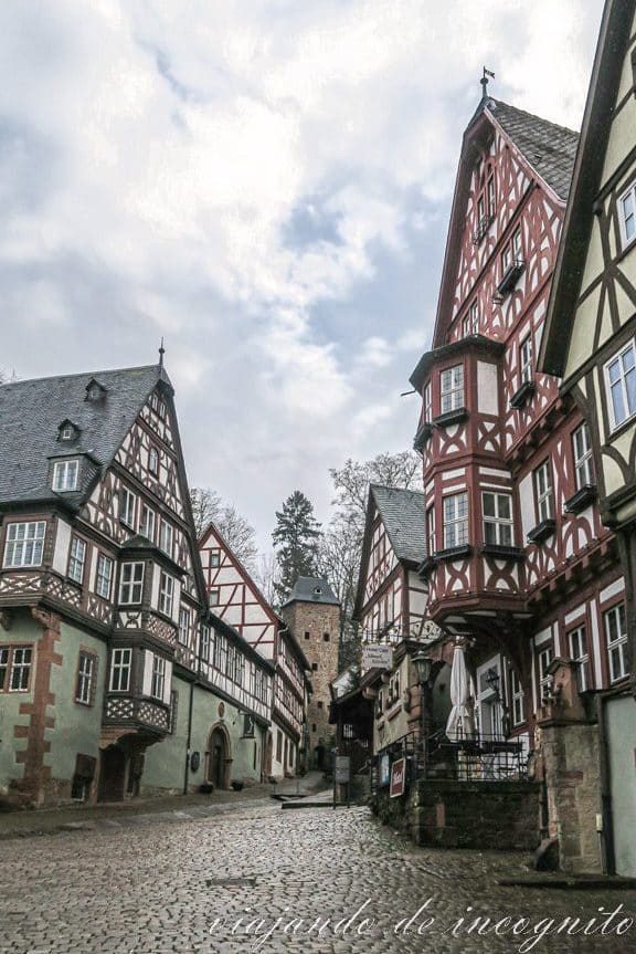 Calle en cuesta flanqueada por casas de entramado de madera con bonitos miradores y con una antigua torre de la muralla al fondo