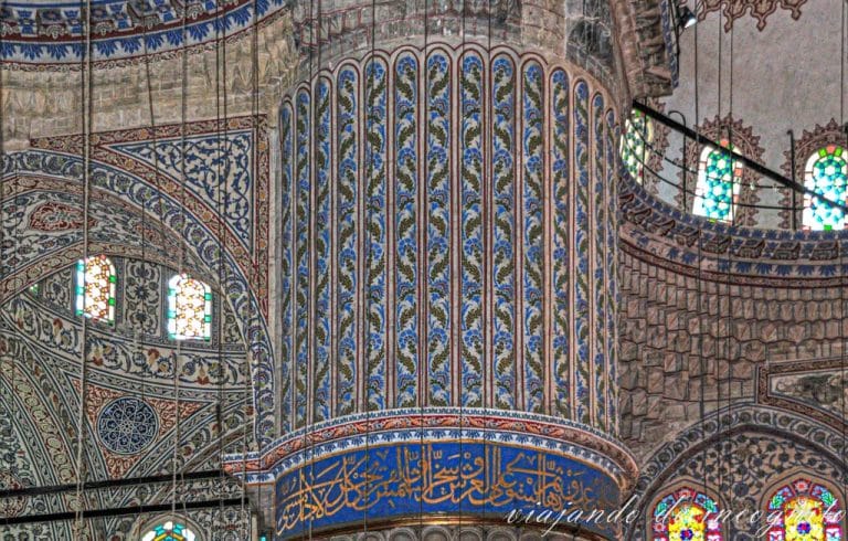 Columna y cúpulas de la mezquita azul decoradas con diferentes formas geométricas en colores azul, rojo y dorado