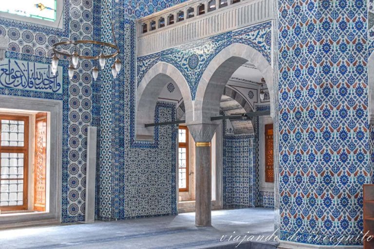 Interior luminoso de la Mezquita Rüstem Pasha con las paredes cubiertas con azulejos azules y blancos de diferentes motivos geométricos. Las alfombras que cubren el suelo también son azules