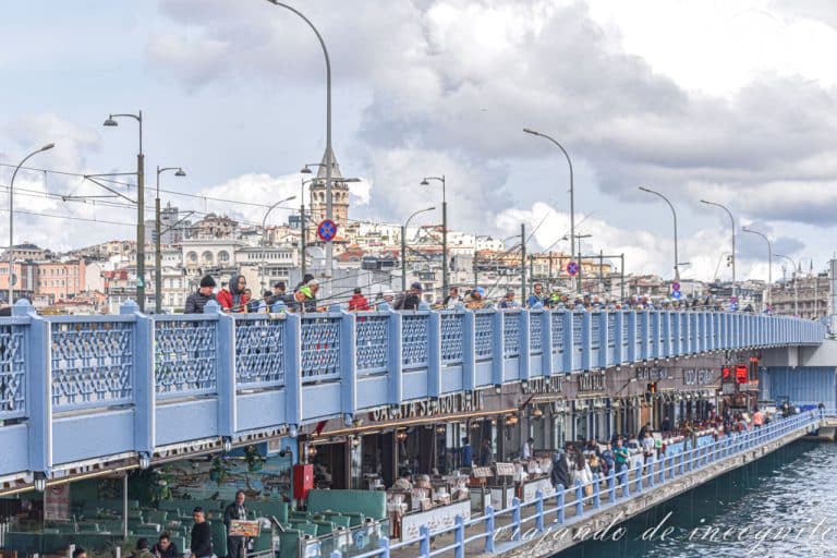 Puente de Gálata con pescadores en la parte superior y gente sentada en las terrazas de varios restaurantes en su parte inferior