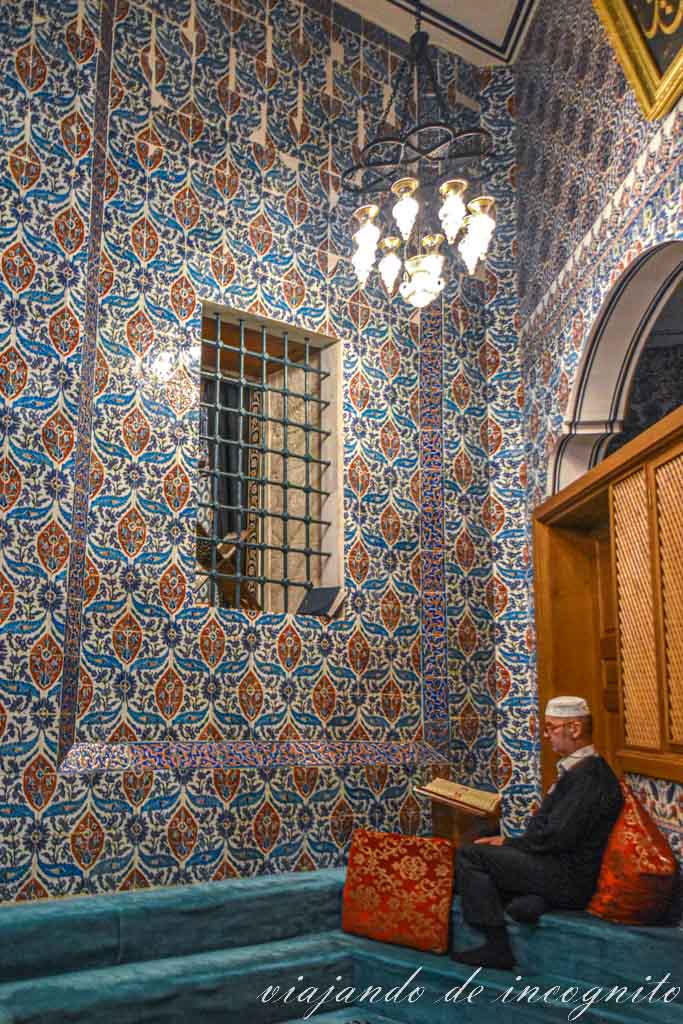 Hombre sentado y rezando en el mausoleo decorado con azulejos de Ebu Eyüp el-Ansari