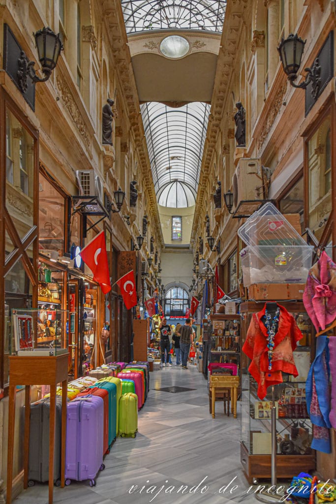 Interior del Pasaje Avrupa con numerosas tiendas con banderas turcas a la puerta y techo de cristal