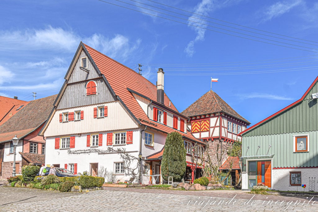 Herrería en Bad Teinach-Zavelstein, casa blanca de ventanas rojas con un gran tejado y una pequeña torre de entramado de madera