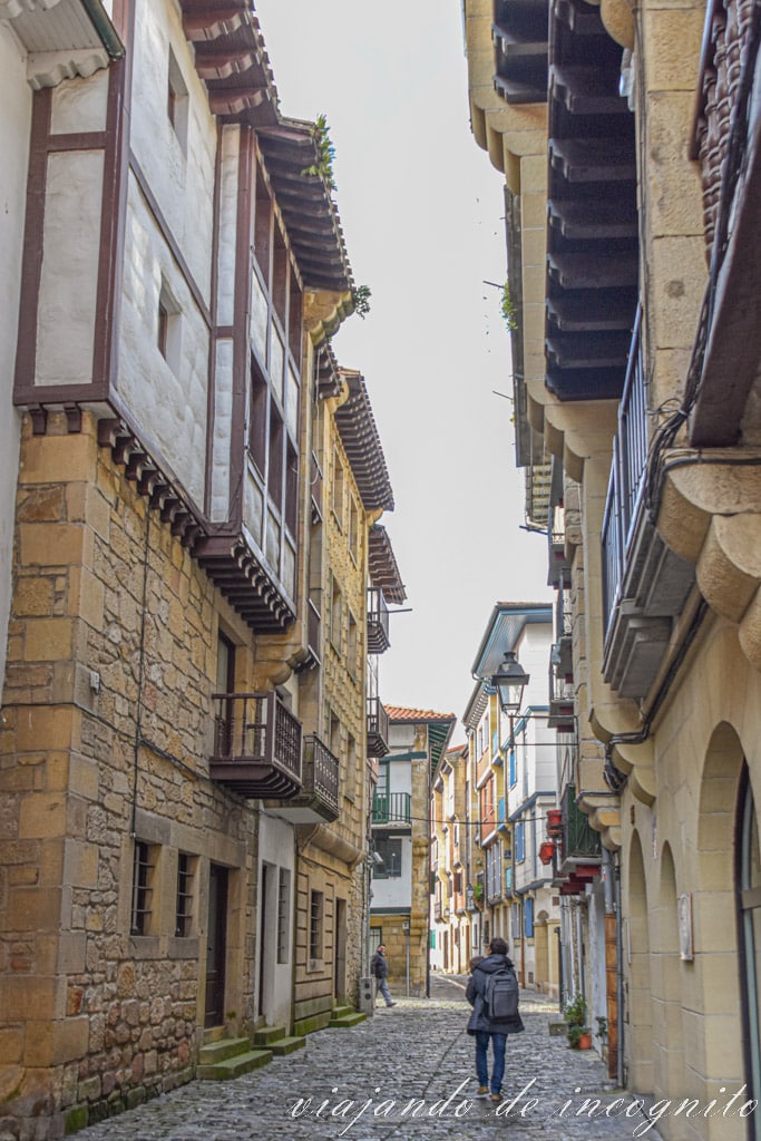 Persona paseando por una calle empedrada de casas de piedra en Hondarribia