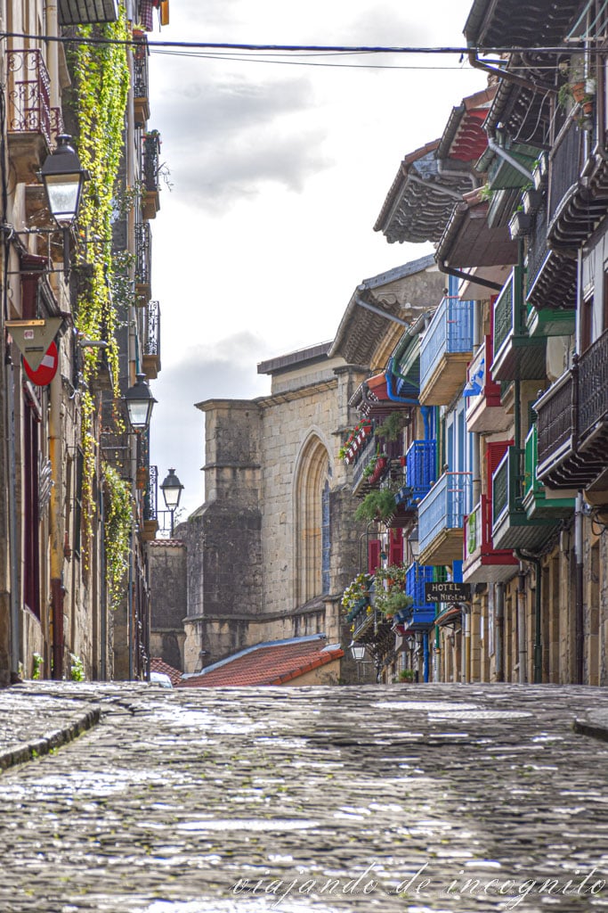 Calle empedrada de Hondarribia con casas de balcones de colores e iglesia al fondo