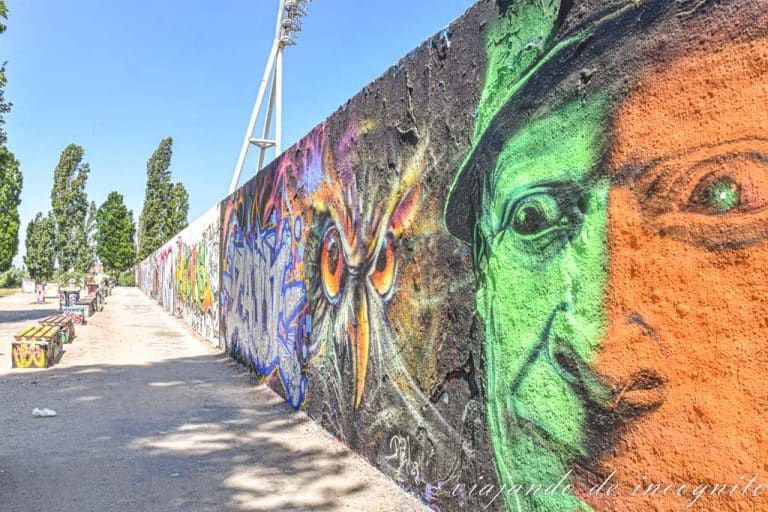Restos del muro en el parque del Muro con murales, cara hombre verde y naranja