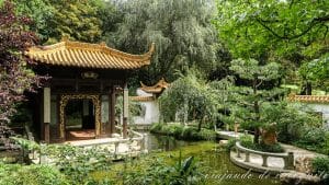 Pabellón de verano rodeado de árboles y junto a un estanque en el jardín chino del Westpark en Múnich.