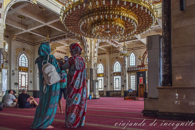 Dos mujeres turistas tapadas en el interior de la mezquita Al Mina de Hurghada donde se ve una lampara de gran tamaño
