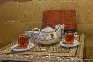 Tetera decorada con letras doradas y la imagen de una famosa cantante junto a dos vasos llenos de té