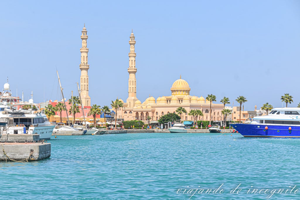 Mar de color turquesa en Hurghada con la gran mezquita de color blanco y barcos amarrados en el puerto