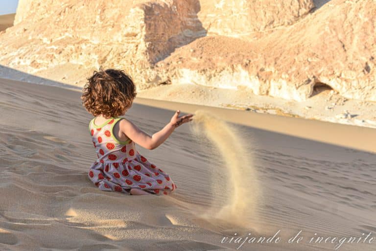 Niña pequeña jugando con la arena del desierto