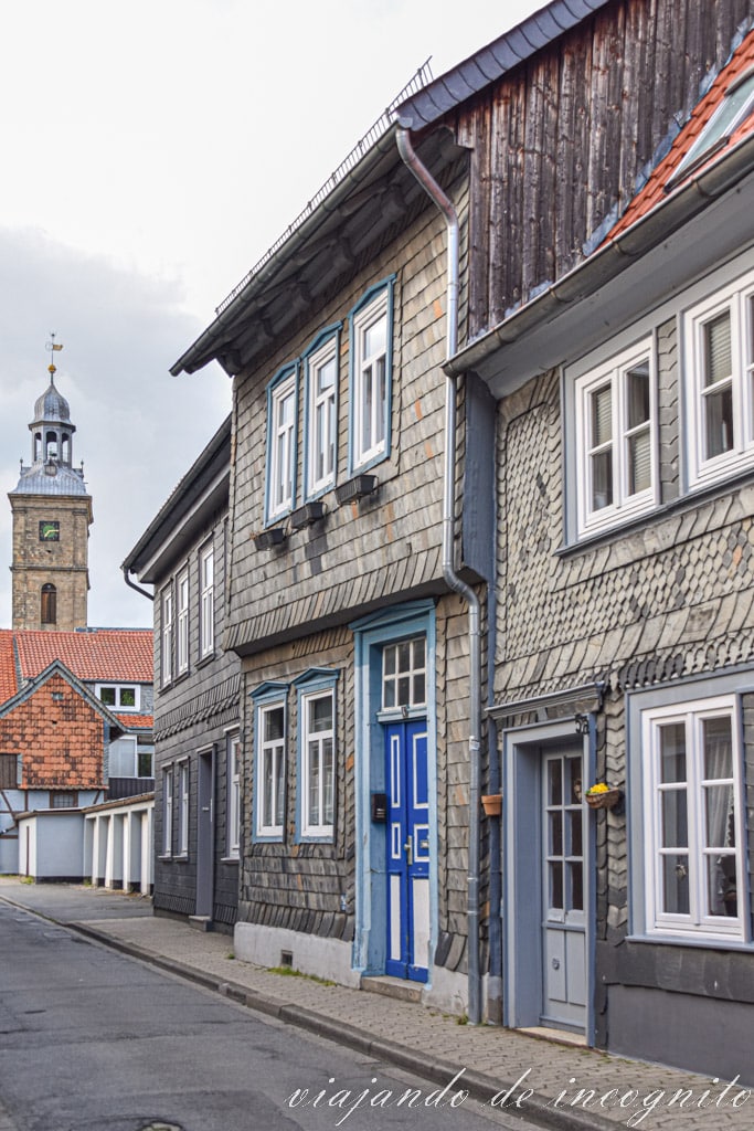 Calle empedrada de Goslar con la torre de una iglesia al fondo y una de las puertas de las casas de color azul