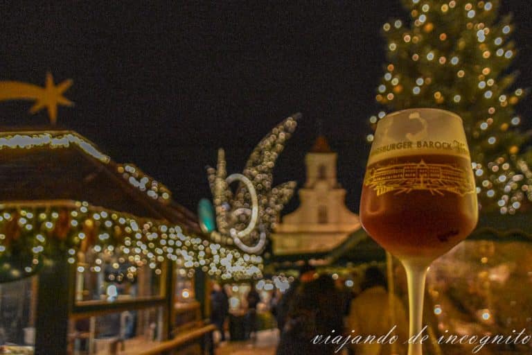 Copa de vino del mercado de navidad de Ludwigsburg frente a los puestos del mercado iluminados y con la iglesia de la ciudad al fondo