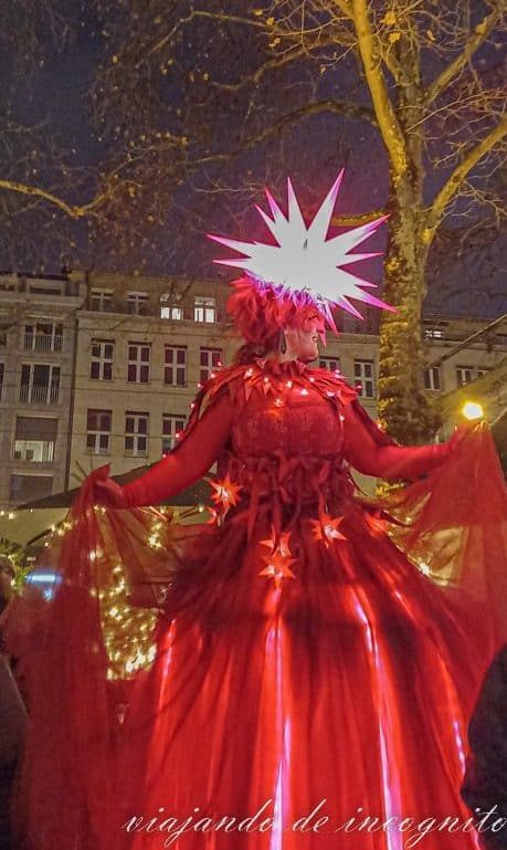 Mujer disfrazada con un vestido rojo y una estrella iluminada en la cabeza en el mercado de navidad de Neumarkt