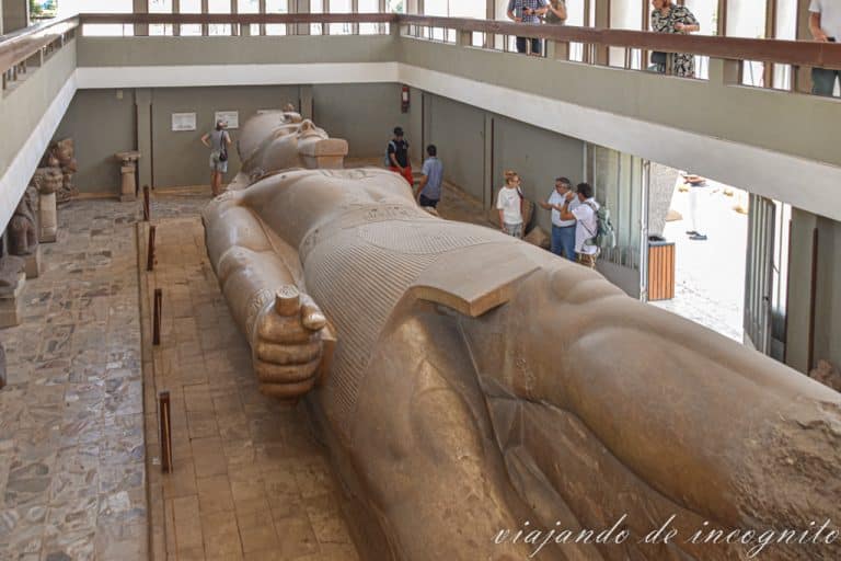 Personas viendo la escultura colosal de Ramses II en el museo de Menphis, tanto en la planta baja como en la superior