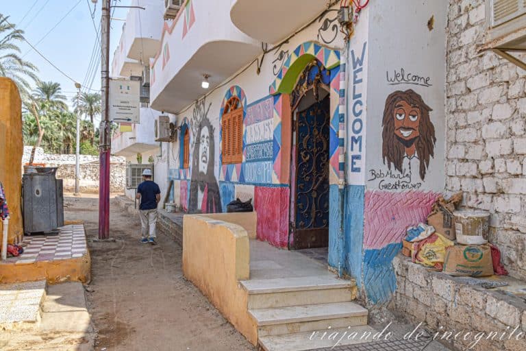 Un hombre con sombrero blanco pasea frente a la entrada de la Guest House Bob Marley decorada con imágenes del cantante