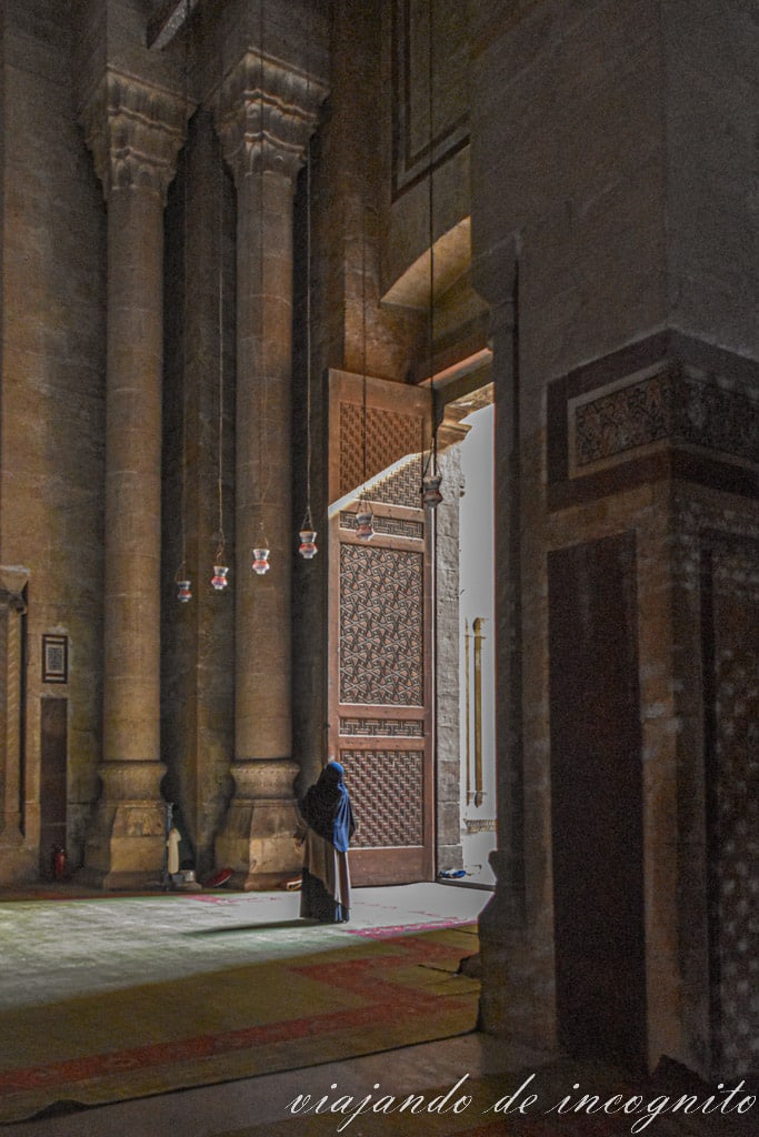 Mujer con la cabeza cubierta mira hacia al techo en el interior de la mezquita al-Rifai
