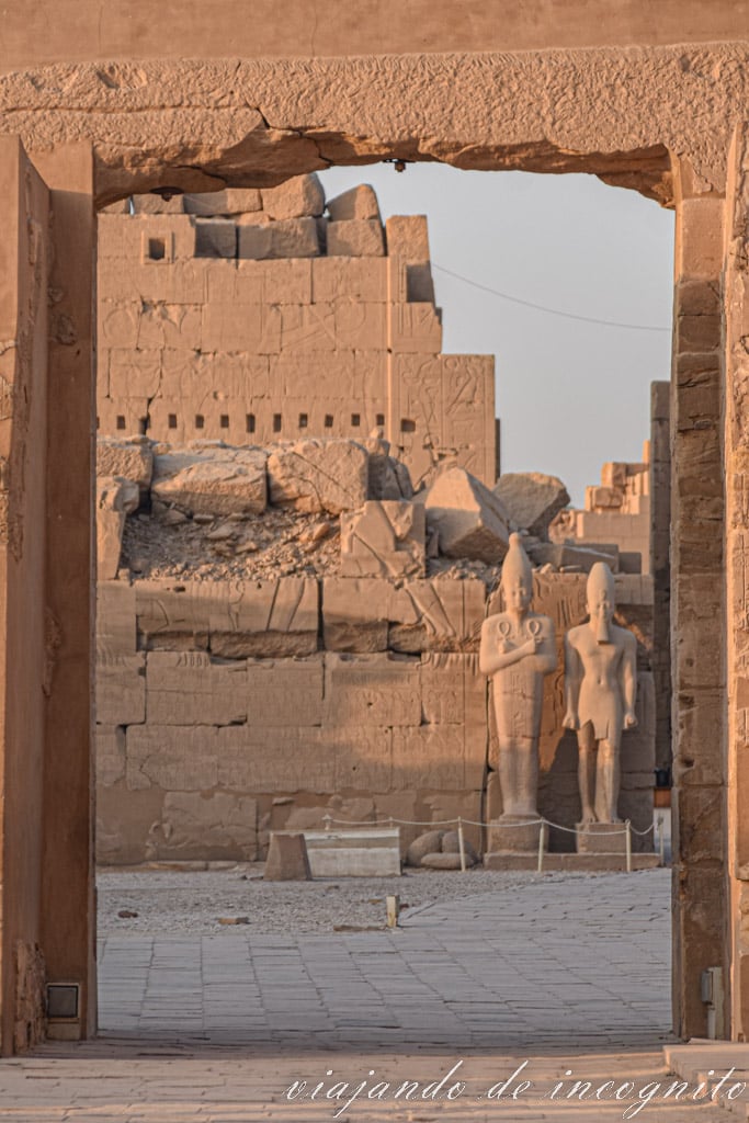 Ruinas del recinto de Amon en el templo de Karnak. Dos esculturas de faraones se ven a través de una puerta.