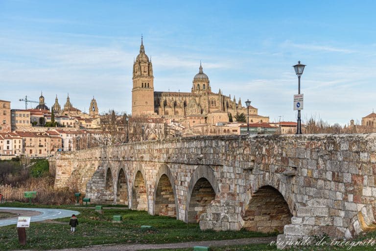 Una niña juega junto al puente romano