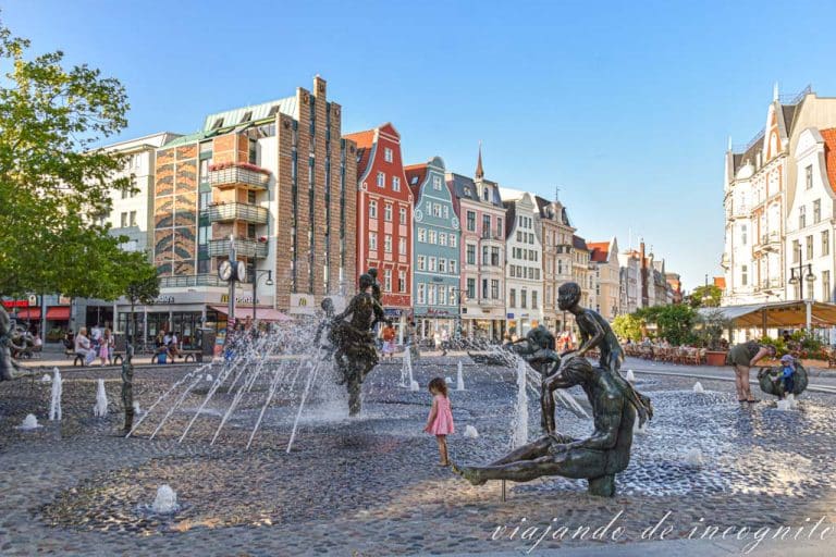 Niños jugando entre los chorros de la fuente de la plaza de la universidad de Rostock