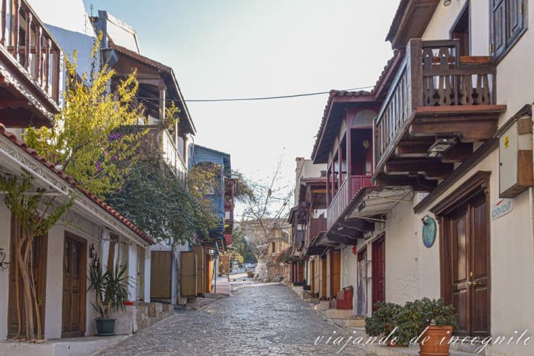 Calle empedrada del centro de Kas con los típicos balcones de madera y la tumba del Rey al fondo
