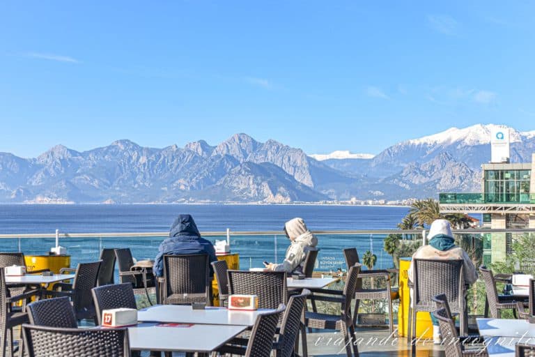 Dos personas toman algo en una terraza en Antalya en febrero. Así, llevan chamarra y al fondo se ven los montes nevados