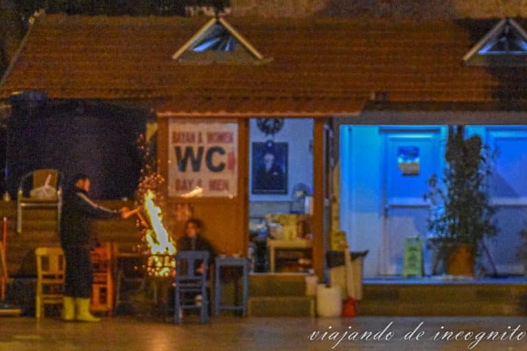 Una pareja se calienta en una hoguera frente a unos baños públicos en la plaza puncipal de Kas en febrero
