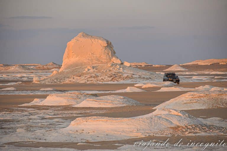 Un todoterreno conduce por el desierto blanco al atardecer
