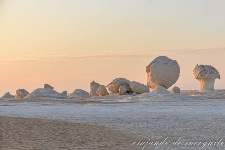 Atardecer en el desiert blanco. Se ven varias formaciones rocosas en el horizonte