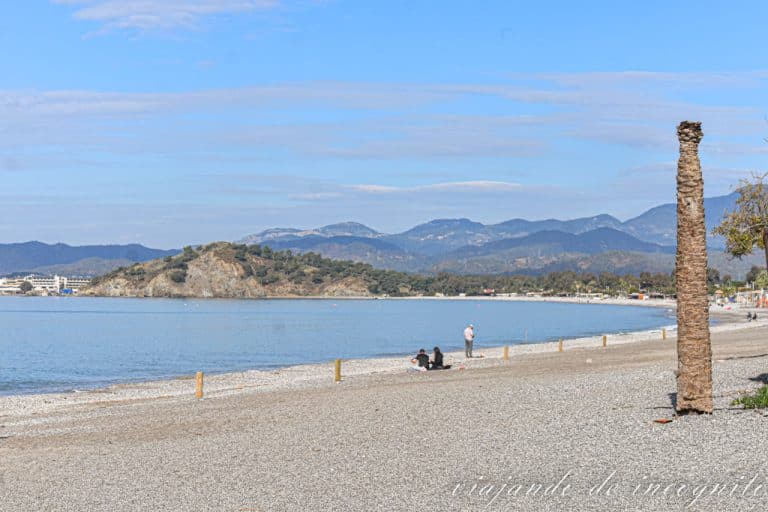 Playa Calis en Fethiye. Está vacía, sólo hay un par de personas sentadas en la arena y alguna caminando por la orilla.