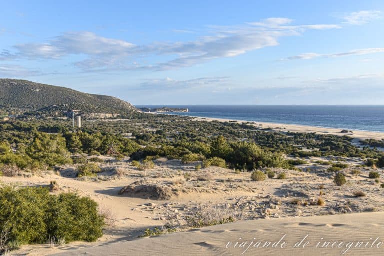 Una pareja observa el atardecer en las dunas de Patara conn las ruinas de la ciudad antigua t la playa al fondo