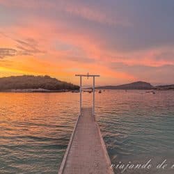 Atardecer en la playa Rilinda de Ksamil. Se ve el paseo de madera que termina en un arco blanco.