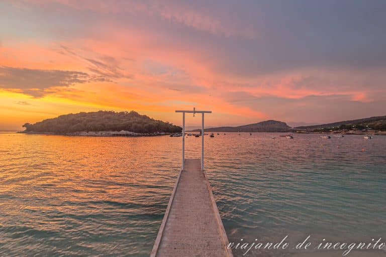 Atardecer en la playa Rilinda de Ksamil. Se ve el paseo de madera que termina en un arco blanco.