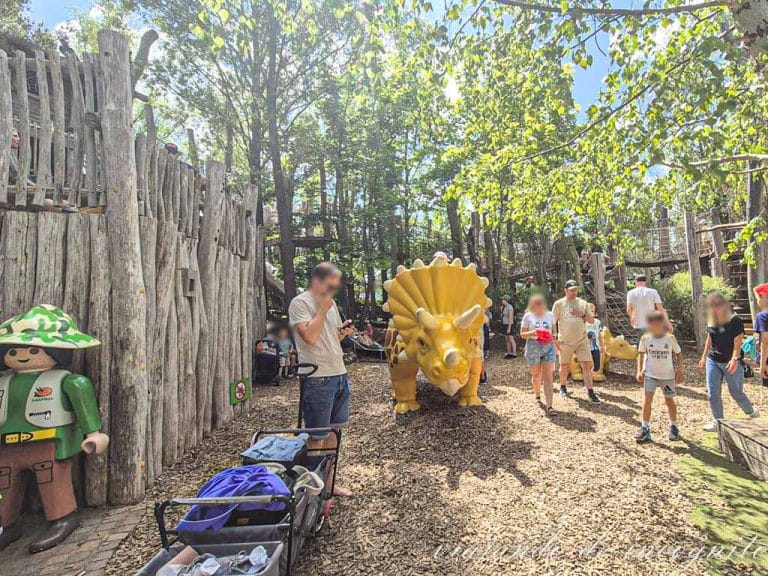 Un hombre mira el móvil frente a una estatua de un dinosaurio amarillo