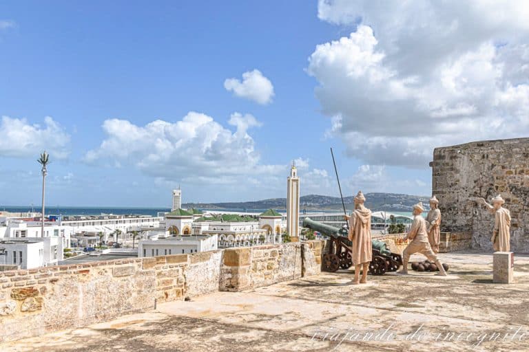 Un grupo de esculturas representan a varios soldados disparando un cañón en el centro de interpretación de las fortificaciones de Tánger. Al fondo se ve la mezquita del Puerto