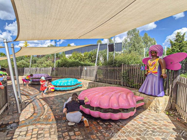 Varios niños buscan tesoros dentro de grandes conchas de colores.