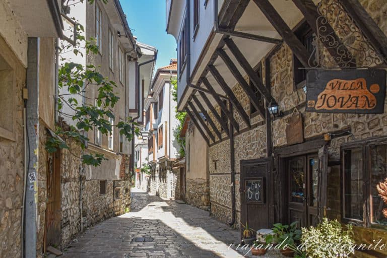 Calle de Ohrid con las casas típicas de la ciudad que tienen la planta baja de piedra y las superiores pintadas en blanco.