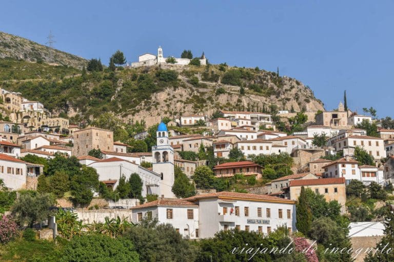 Vista general de Dhermi y sus casas blancas de tejados naranjas. También se ve la basílica ortodoxa con su tejado azul.